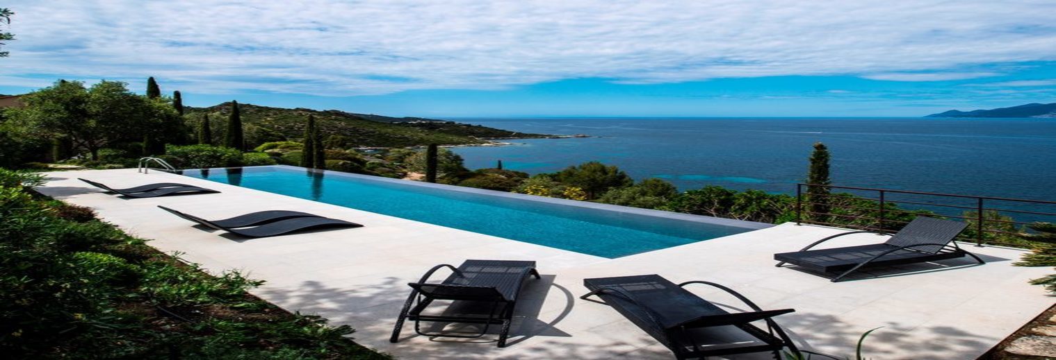 Piscine à débordement avec transats face à la baie